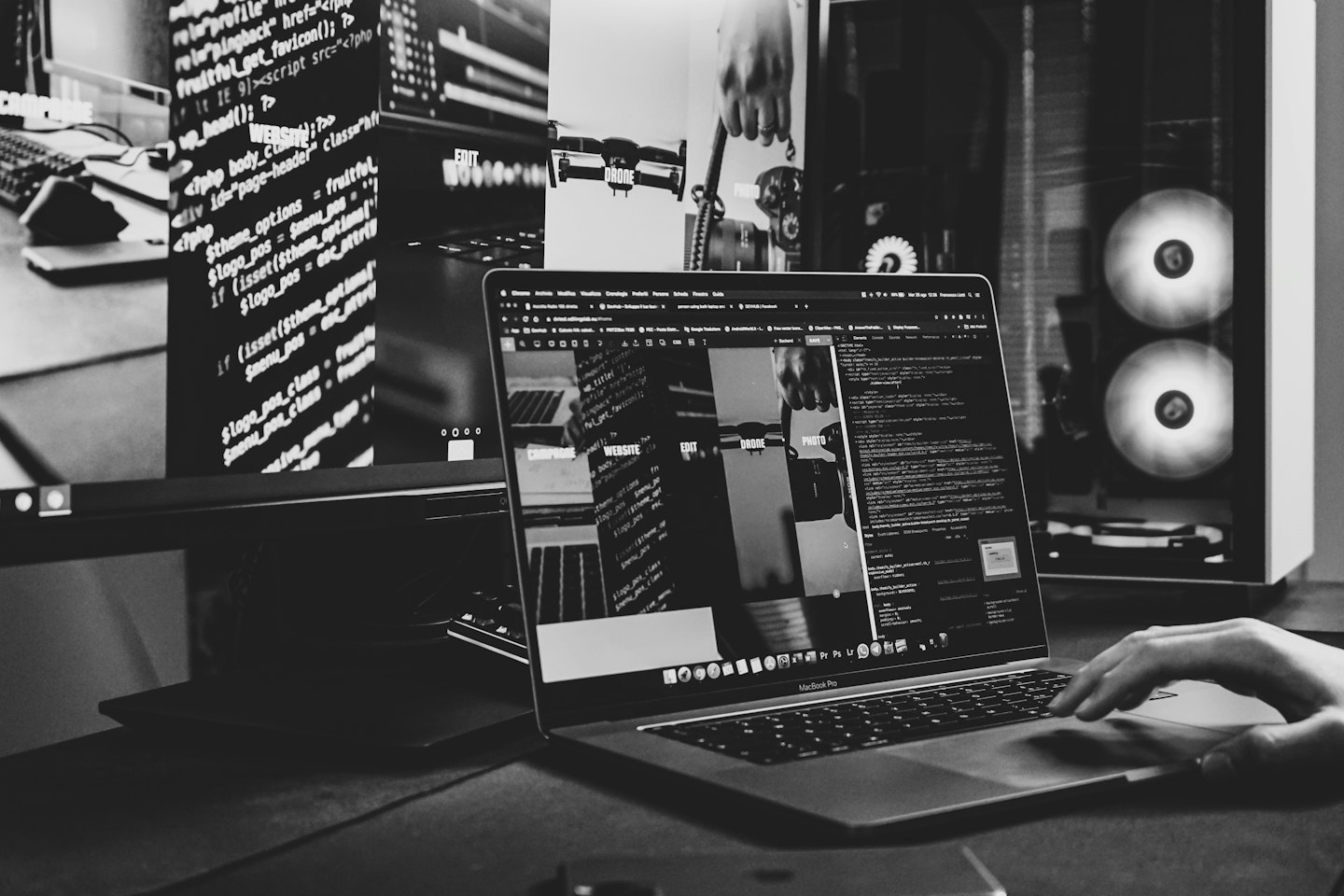 Tangan menggunakan trackpad MacBook Pro dengan kode di layar.