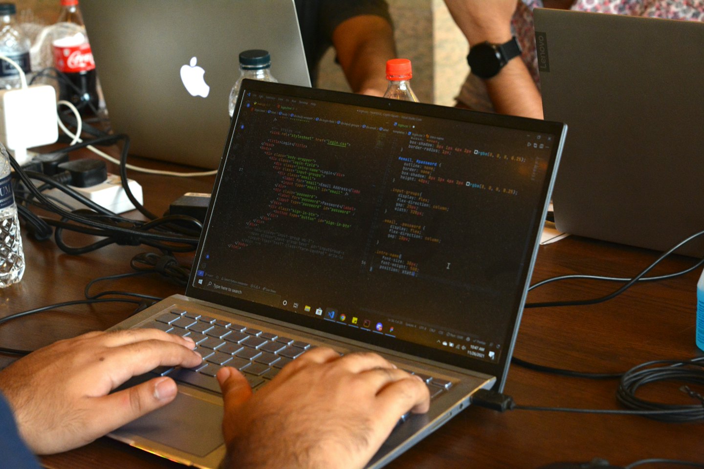 Tangan Asia Selatan mengetik kode komputer di laptop.