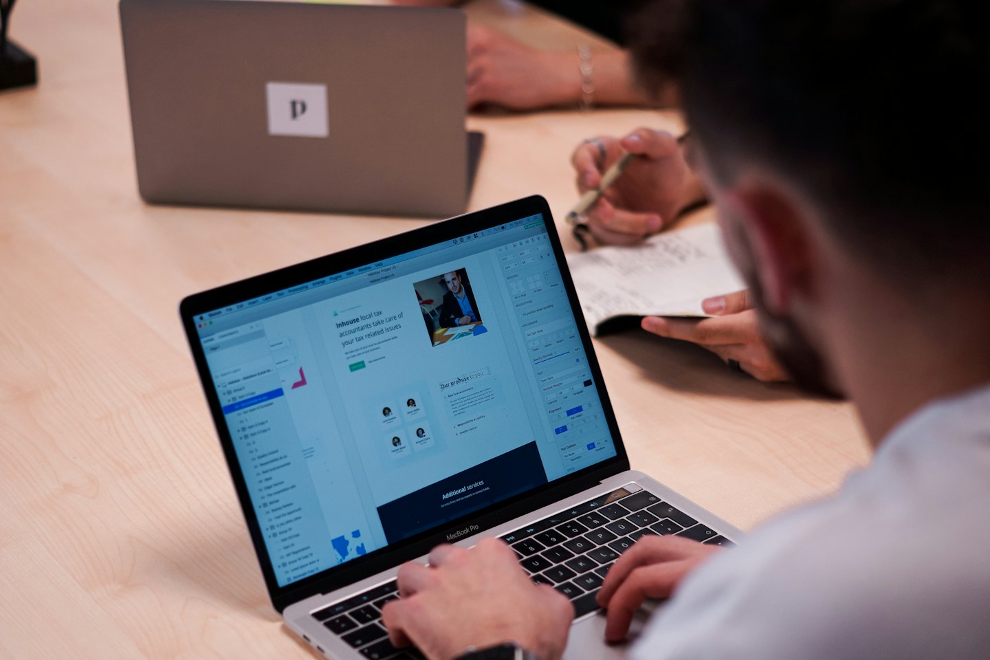 Tangan mengetik di laptop menampilkan desain situs web.